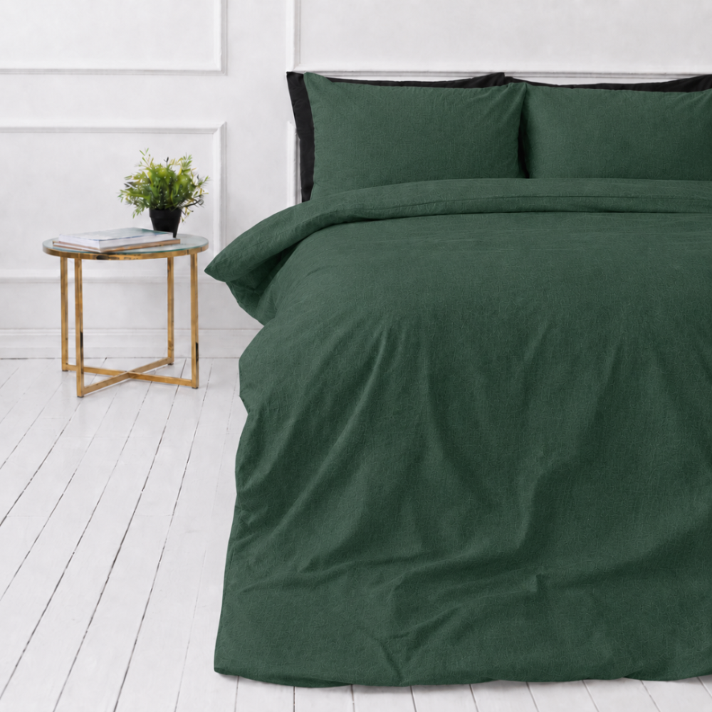 Lina gultas veļas „Linen Dark Green“. Gultas veļas komplekti 150x200, 140x200 cm, 150x200 cm, 160x200 cm, 180x200 cm, 200x200 cm, 200x220 cm, 220x240 cm. Tumši zaļš lina gultas veļas komplekts uz baltas grīdas ar naktsgaldiņu un podiņaugu.
