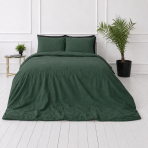 Lina gultas veļas „Linen Dark Green“. Gultas veļas komplekti 150x200, 140x200 cm, 150x200 cm, 160x200 cm, 180x200 cm, 200x200 cm, 200x220 cm, 220x240 cm. Guļamistabas skats no stūra: tumši zaļa lina sega un spilveni.